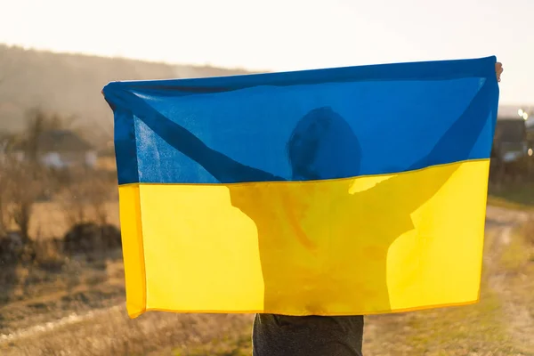 Mulher segurando uma bandeira amarela e azul da Ucrânia ao ar livre — Fotografia de Stock