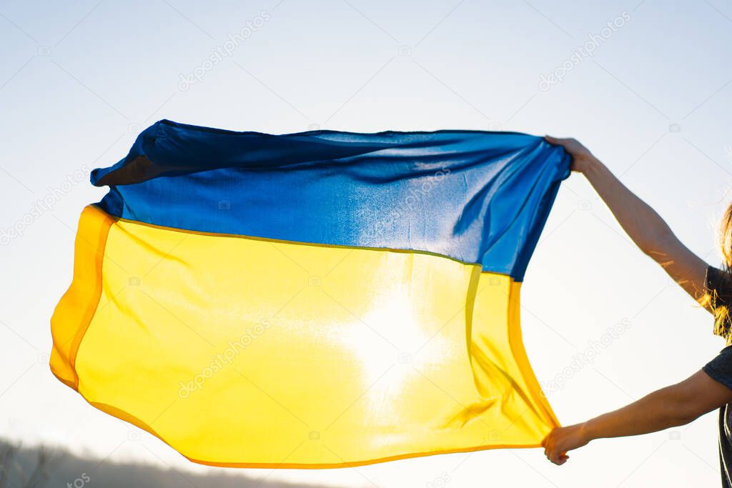 Woman holding a yellow and blue flag of Ukraine in outdoors