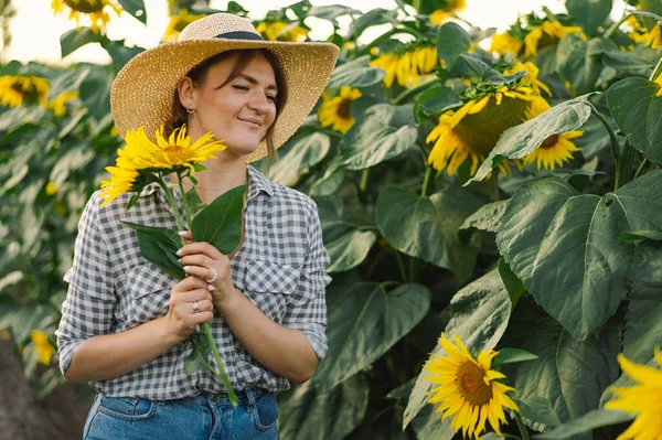 Wanita muda cantik dengan bunga matahari menikmati alam dan tertawa di musim panas bunga matahari. — Stok Foto