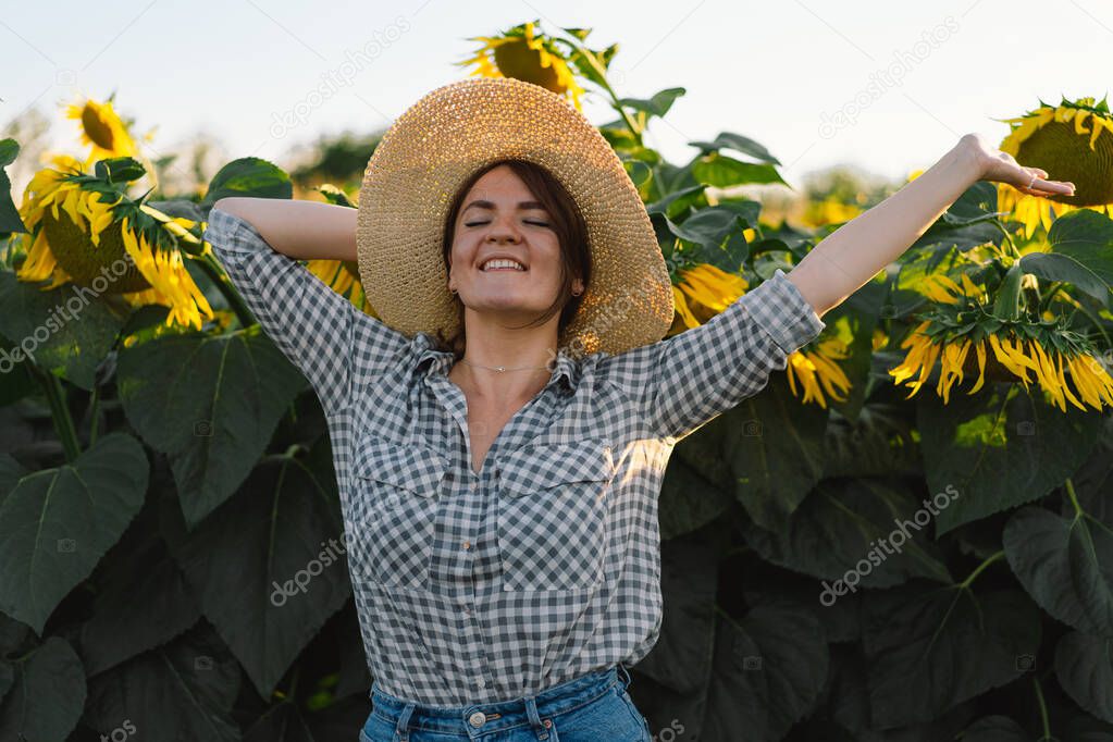 Beautiful young woman with sunflowers enjoying nature and laughing on summer sunflower field.