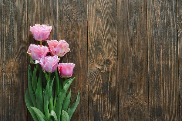 Na dřevěném pozadí ležely čerstvé tulipány. Stylové přání k pozdravu — Stock fotografie