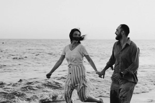 Foto in bianco e nero. Giovane coppia romantica che balla voltandosi dal mare. — Foto Stock
