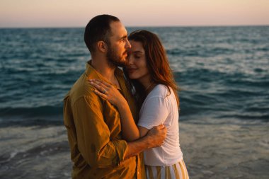 Young romantic couple dancing turning around by sea. Seascape at sunset with beautiful sky