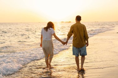 Young romantic couple dancing turning around by sea. Seascape at sunset with beautiful sky