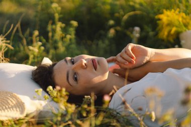 Güzel romantik bir kadın yaz otlağında bir battaniyenin üzerinde yatıyor. Kendine zaman ayır..