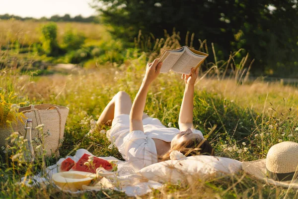 Mladá žena čte knihu na venkovním poli. Čtení a relaxace — Stock fotografie
