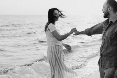 Siyah beyaz fotoğraf. Genç romantik çift denizde dans ediyor..