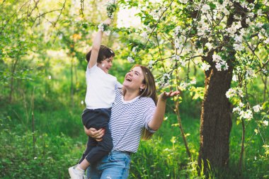 Anneler Günün kutlu olsun. Anne ve küçük oğlu bahar bahçesinde altın saat boyunca. Anne ve oğul.