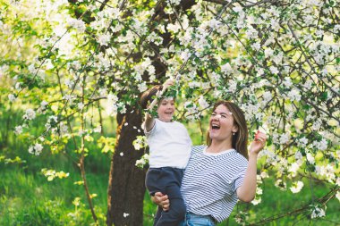 Anneler Günün kutlu olsun. Anne ve küçük oğlu bahar bahçesinde altın saat boyunca. Anne ve oğul.