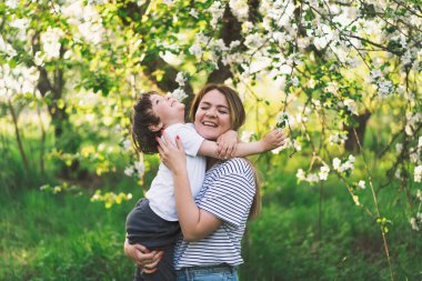 Anneler Günün kutlu olsun. Anne ve küçük oğlu bahar bahçesinde altın saat boyunca. Anne ve oğul.