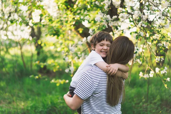 Anneler Günün kutlu olsun. Anne ve küçük oğlu bahar bahçesinde altın saat boyunca. Anne ve oğul.