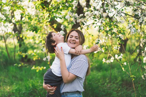 Anneler Günün kutlu olsun. Anne ve küçük oğlu bahar bahçesinde altın saat boyunca. Anne ve oğul.