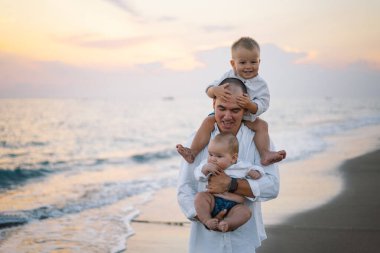Baba ve çocuklar sahilde oynuyorlar. Babam ve o gün batımının tadını çıkarıyorlar..
