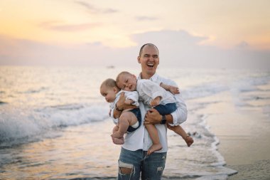 Baba ve çocuklar sahilde oynuyorlar. Babam ve o gün batımının tadını çıkarıyorlar..