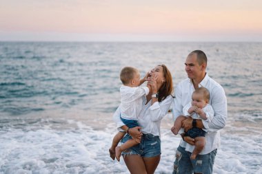 Mutlu bir aile, yaz tatilinde sahilde plaj oynarken eğleniyor..