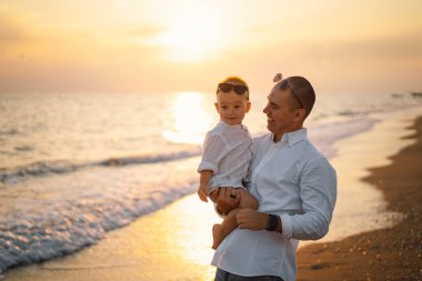 Baba ve bebek kumsalda oynuyorlar. Babam ve o gün batımının tadını çıkarıyorlar..