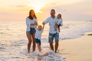 Mutlu bir aile, yaz tatilinde sahilde plaj oynarken eğleniyor..