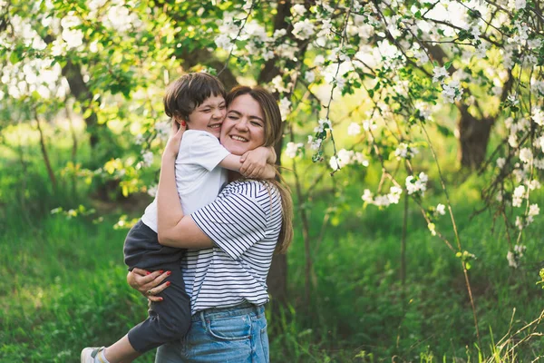 Anneler Günün kutlu olsun. Anne ve küçük oğlu bahar bahçesinde altın saat boyunca. Anne ve oğul.