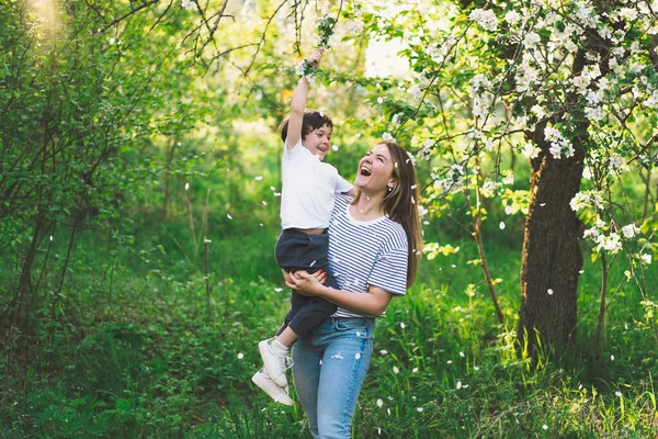 Buona festa della mamma. Madre con piccolo figlio nel giardino primaverile durante l'ora d'oro. Mamma e figlio — Foto Stock