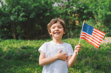 Küçük mutlu vatansever çocuk Amerikan bayrağı taşıyor..