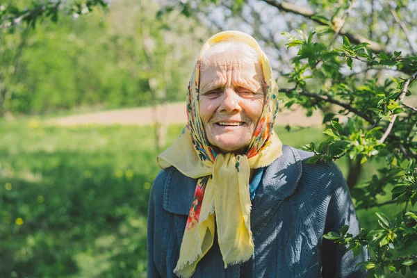 Portrait of an old happy woman in a yellow headscarf. — Stock Photo, Image