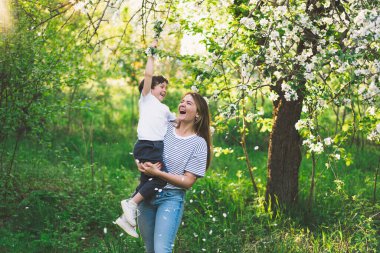 Anneler Günün kutlu olsun. Anne ve küçük oğlu bahar bahçesinde altın saat boyunca. Anne ve oğul.