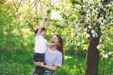 Anneler Günün kutlu olsun. Anne ve küçük oğlu bahar bahçesinde altın saat boyunca. Anne ve oğul.
