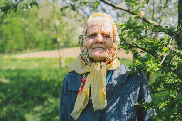 Retrato de uma velha mulher feliz em um lenço amarelo. — Fotografia de Stock