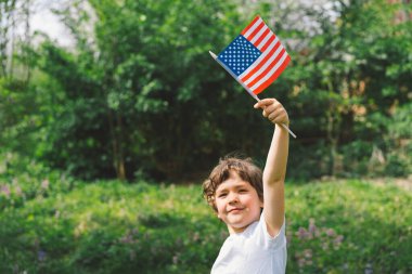 Amerikan bayrağı tutan küçük mutlu vatansever çocuk. ABD 4 Temmuz 'u kutluyor. Bağımsızlık günün kutlu olsun.