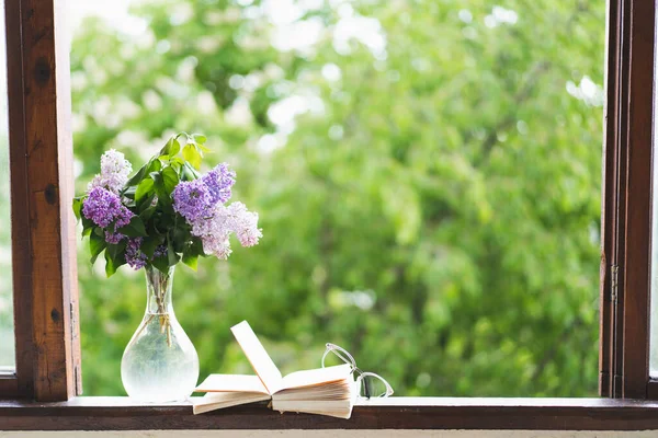 Ahşap bir pencerede kitap, gözlük ve leylak. Romantik bir kavram. Klasik stil