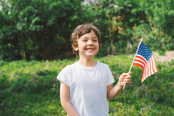 Happy little patriotic boy holding American flag. USA celebrate 4th of July. Happy independence day