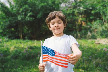 Amerikan bayrağı tutan küçük mutlu vatansever çocuk. ABD 4 Temmuz 'u kutluyor. Bağımsızlık günün kutlu olsun.