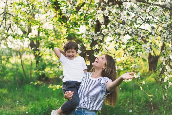 Mother with little baby son in spring garden during golden hour. Mom and son are active in nature. Family walks in a spring garden. Happy mothers day