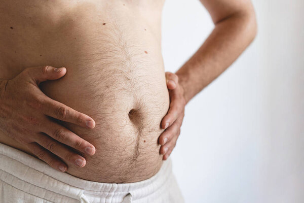 Close up of fat mans belly. Perhaps the concept of abdominal pain, bloating. Health concept.