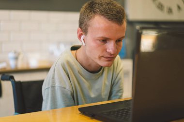 Mutfakta cep telefonuyla konuşan yakışıklı, engelli bir adam. Engelli biri. Görüntülü konuşma ya da arama. Özürlü bir adamın portresi. İyimser gülümseyen engelli adam.