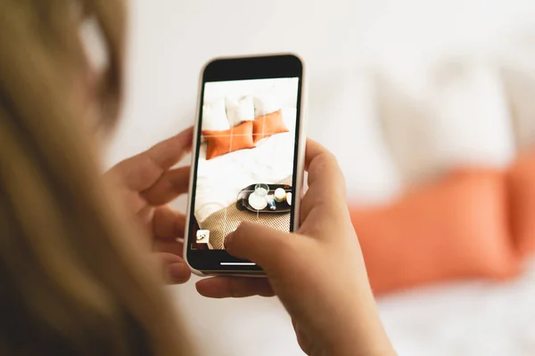 Video blog. A young woman is filming home goods for her online store on her phone camera. Running a video blog. A vlogger broadcasts online using a phone. Social networks,stay at home and quarantine.