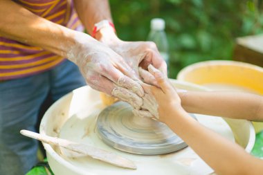 Potter dışarıda çömlek çarkında kilden bir nesne yapıyor. Elleri çömlek çarkında kil döşeyen bir zanaatkar. Potter kil modelleme ana sınıfını gösteriyor.