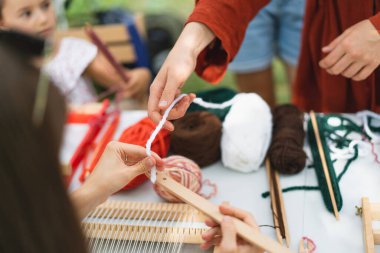 Üstat sınıfında örgü ören küçük bir halı ören kız. Kız manuel masa tezgahında nasıl örüleceğini öğreniyor. Yaradılış süreci. El yapımı konsept