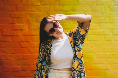 Summer portrait of happy smiling young woman with sunglass on colorful orange background