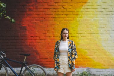 Renkli turuncu arka planda güneş gözlüklü mutlu genç bir kadının yaz portresi.