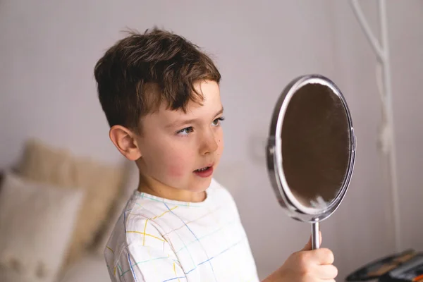 Speech therapy concept. Cute little boy pronouncing sound O looking at mirror doing an online Speech therapy lesson through a laptop