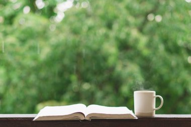 Sıcak yaz durgun hayatı: bir fincan sıcak çay ve klasik pencere pervazı ve yağmur üzerine açık bir kitap. Daire. Yazın yağmur yağar.