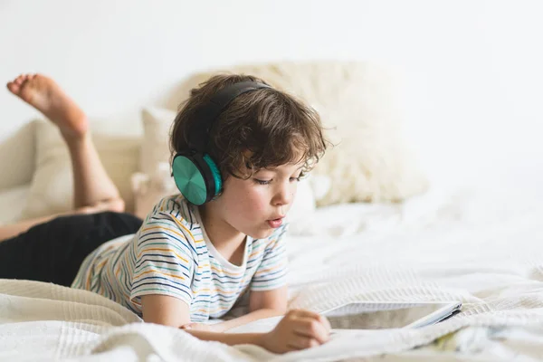 Cute Boy Lying Bed Home Playing Tablet Reading Online Listening — Stok Foto