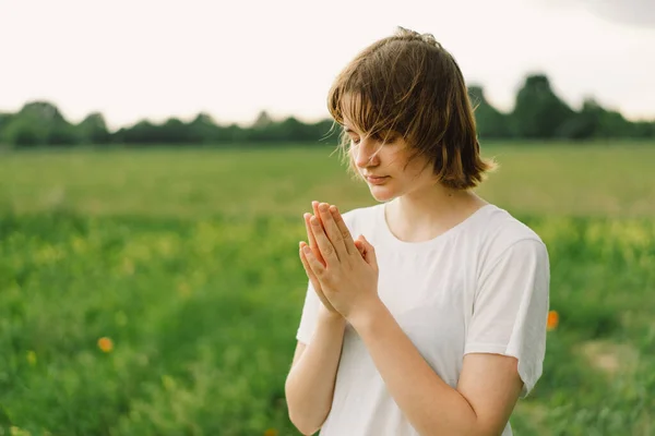 Teenager Girl closed her eyes, praying. Hands folded in prayer concept for faith, spirituality and religion. Peace, hope, dreams concept