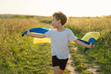 Ukraines Independence Day. Ukrainian child boy in white t shirt with yellow and blue flag of Ukraine in field. Flag of Ukraine. Constitution day. Stand with Ukraine and Save