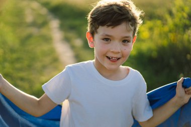 Ukraines Independence Day. Ukrainian child boy in white t shirt with yellow and blue flag of Ukraine in field. Flag of Ukraine. Constitution day. Stand with Ukraine and Save