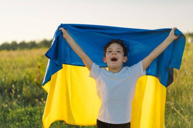 Ukraines Independence Day. Ukrainian child boy in white t shirt with yellow and blue flag of Ukraine in field. Flag of Ukraine. Constitution day. Stand with Ukraine and Save