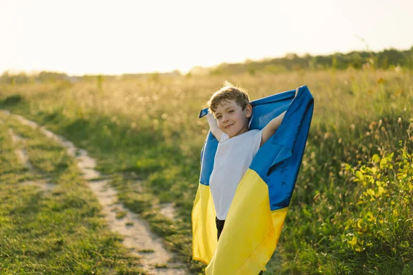 Ukraines Independence Day. Ukrainian child boy in white t shirt with yellow and blue flag of Ukraine in field. Flag of Ukraine. Constitution day. Stand with Ukraine and Save