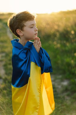 Ukraynalı çocuk gözlerini kapadı ve Ukrayna 'daki savaşı gün batımında bir tarlada durdurmak için dua etti. İnanç, maneviyat ve din için dua kavramında eller kavuşturuldu. Rusya 'nın Ukrayna' ya karşı savaşı. Savaşı Durdur