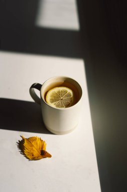 Dekoratif balkabakları, kurumuş yapraklar, aksesuarlar ve ahşap zemin üzerinde limonlu çay. Üst görünüm, boşluğu kopyala. Sonbahar konsepti